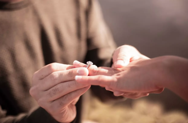 a man slides a ring on a woman's finger