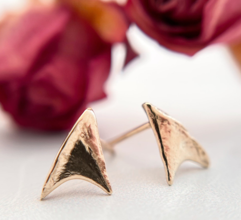 Rose thorn solid gold studs in front of two roses